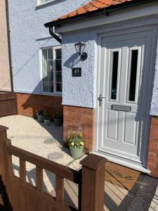 una casa con una puerta blanca y una valla en Nina's Cottage - Southwold, en Southwold