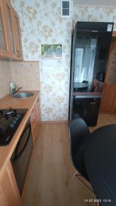 a kitchen with a sink and a black refrigerator at Celtnieku 14 in Ventspils