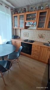 a kitchen with wooden cabinets and a table and a stove at Celtnieku 14 in Ventspils