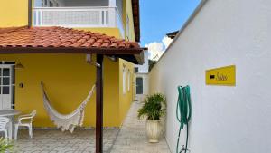 un edificio blanco y amarillo con una hamaca en el patio en Kalug - Suíte CASAL independente em Guest house en Ilhéus