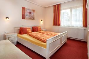 ein Schlafzimmer mit einem Bett mit orangefarbener Bettwäsche und einem Fenster in der Unterkunft Hotel Garni Tannenhof in Flachau