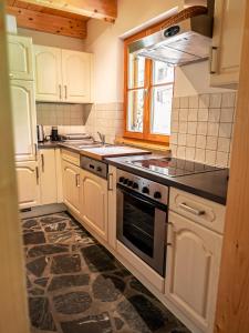 德哥米斯的住宿－Alpin-Hütten auf der Turracherhöhe - Haus Fuchs by S4Y，厨房配有白色橱柜和炉灶烤箱。