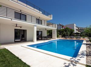 a swimming pool in front of a house at Family House "Villa Gyra" with Private Swimming Pool, Indoor BBQ, Gym and Gaming room! in Podstrana