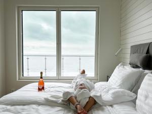 a person laying on a bed with a bottle of beer at HavsVidden Resort in Geta