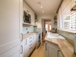 a kitchen with white cabinets and a sink and a window at Minster Cottage - Cathedral Quarter with Permit Parking in Lincoln