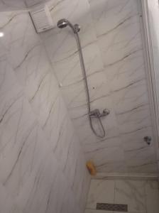 La salle de bains est pourvue d'une douche et d'un mur en marbre blanc. dans l'établissement maison Halima, à Ifrane