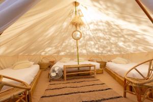 a room with two beds and two chairs in a tent at HolaCamp Barcelona in Gavà