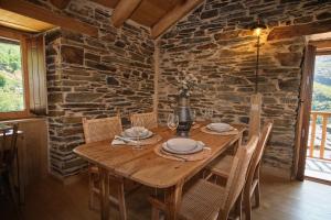 una mesa de madera en una habitación con una pared de piedra en Lar da cima, en Folgoso
