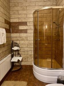 a bathroom with a glass shower and a chair at ЕДБУРГ Готельно-ресторанний комплекс in Nizhnedneprovsk