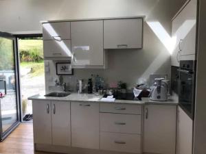 a kitchen with white cabinets and a sink at 3 Quay Cottage Killala. Luxury Sea-Front Cottage in Killala