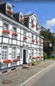 un edificio blanco y negro con macetas en las ventanas en Hotel zur Post Dabringhausen - contactless self check-in, en Wermelskirchen