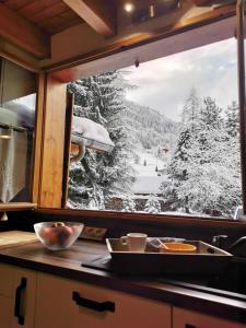 une fenêtre de cuisine avec vue sur une forêt enneigée dans l'établissement Demi-Chalet l'Ancolie -- Prox pistes, aux Carroz d'Arâches