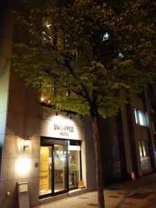 drzewo przed budynkiem w nocy w obiekcie Untapped Hostel w mieście Sapporo