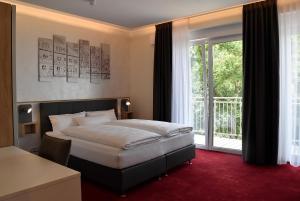 a bedroom with a bed and a large window at Hotel am Waldkasino in Erfurt