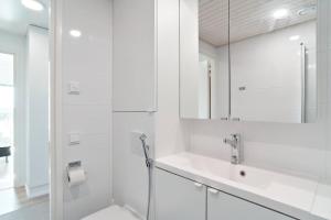 a white bathroom with a sink and a mirror at Norden Homes 2-Bedroom Apartment in Turku