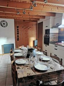 - une table avec des assiettes et des verres dans la cuisine dans l'établissement Demi-Chalet l'Ancolie -- Prox pistes, aux Carroz d'Arâches