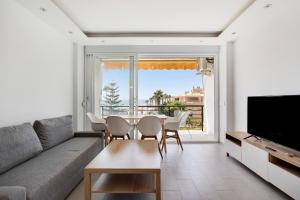 Una sala de estar con un sofá y una mesa con sillas. en Santa Clara, en Torremolinos