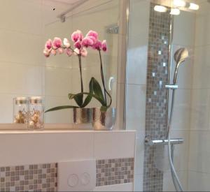 a vase with pink flowers on a shelf in a bathroom at Lodge 2 Bad Harzburg in Bad Harzburg