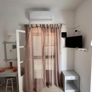 a bedroom with a window with a pink curtain at Panagiotis Rooms in Naousa