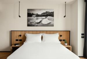 View Place & Spa في نومانا: غرفة نوم بسرير ابيض ولوحة على الحائط