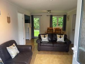 a living room with two leather couches and a table at Bumble Bee Lodge in Liskeard