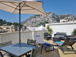 a patio with a table and chairs and an umbrella at Romy Blu in Capri