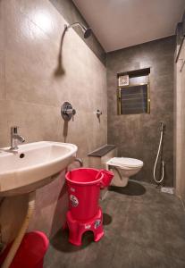 a bathroom with a toilet and a sink and a bucket at Hotel Ranjan Deluxe in Kolhapur