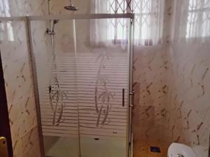 a shower with a glass door in a bathroom at Room in Apartment - Renajoe Ejisu-Kubease in Kubeasi