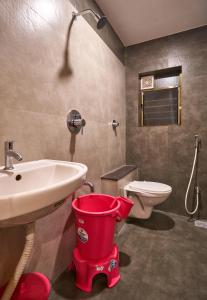 a bathroom with a toilet and a sink and a bucket at Hotel Ranjan Deluxe in Kolhapur