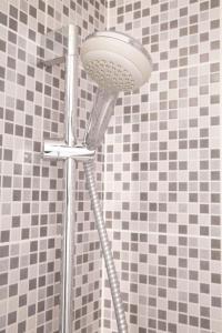 a shower head in a bathroom with black and white tiles at Petit Studio Secret - Coeur de Provence - 4 personnes in Volx