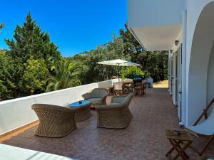 een patio met stoelen en tafels en een parasol bij The hidden villas in Kolios