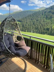 a swinging chair on a porch with a view at Apartment Margherita in Sedrun