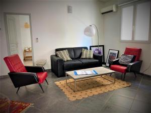 - un salon avec un canapé noir et deux chaises rouges dans l'établissement Correspondances la Colette Pont Du Gard, à Fournès