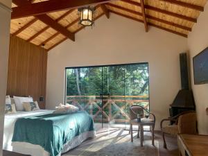 um quarto com uma cama e uma grande janela em Canto da Floresta em Monte Verde