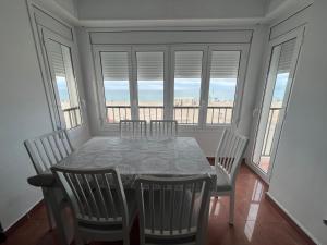 a dining room with a table and chairs and windows at El Bull de Baix a Mar in Torredembarra