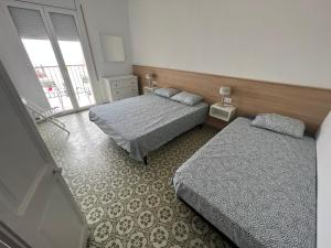 a hotel room with two beds and a window at El Bull de Baix a Mar in Torredembarra