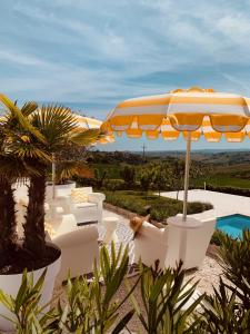 een patio met witte stoelen, een parasol en een zwembad bij Vecchi Maestri Bed & Breakfast in Arcevia
