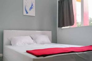 a white bed with a red blanket on it at RedDoorz near Alun Alun Magetan in Magetan