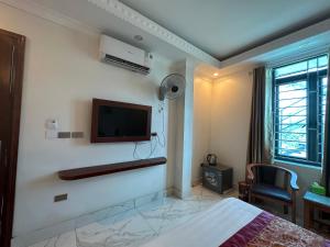 a bedroom with a bed and a tv on the wall at Happy Hotel in Uông Bí