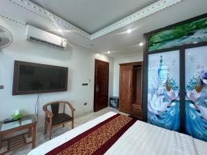 Happy Hotel في Uông Bí: غرفة نوم بسرير كبير وتلفزيون على الحائط