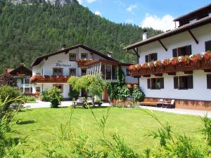 un grand bâtiment blanc avec des fleurs sur ses fenêtres dans l'établissement Haus Adlerkanzel, à Scharnitz