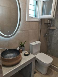 a bathroom with a sink and a toilet and a mirror at Aetherian Suites in Loutra