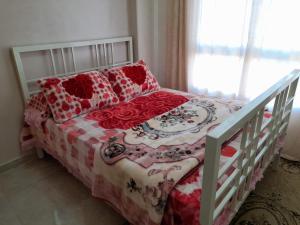 ein Schlafzimmer mit einem weißen Bett mit roten Blumen darauf in der Unterkunft Relax view apartment in Madinat as-Sadis min Uktubar