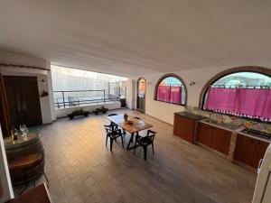 Habitación grande con mesa, sillas y ventanas. en Casa Vacanze Al Vesuvio, en Trecase