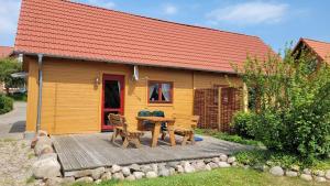 Casa con terraza de madera con mesa y sillas en Ferienhaus Bliev-Hee Nr 4 en Klink