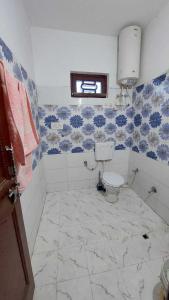 a bathroom with a toilet and blue and white tiles at POP HOME Rozia Homestay in Thanna Mandi