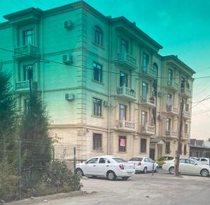 un edificio verde con coches aparcados delante de él en Уютная квартира, en Tashkent