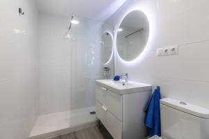 W białej łazience znajduje się umywalka i lustro. w obiekcie Livemálaga Victoria Suites w Maladze
