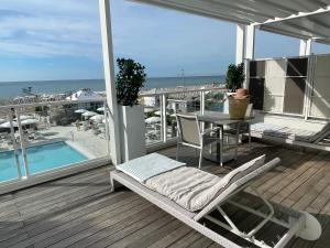 a balcony with a chair and a table and a pool at Hotel Ril in Lido di Jesolo