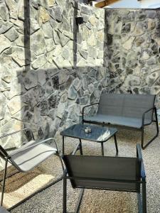 un banco, una mesa y una silla frente a una pared de piedra en Rambling Rooms, en Campomarino